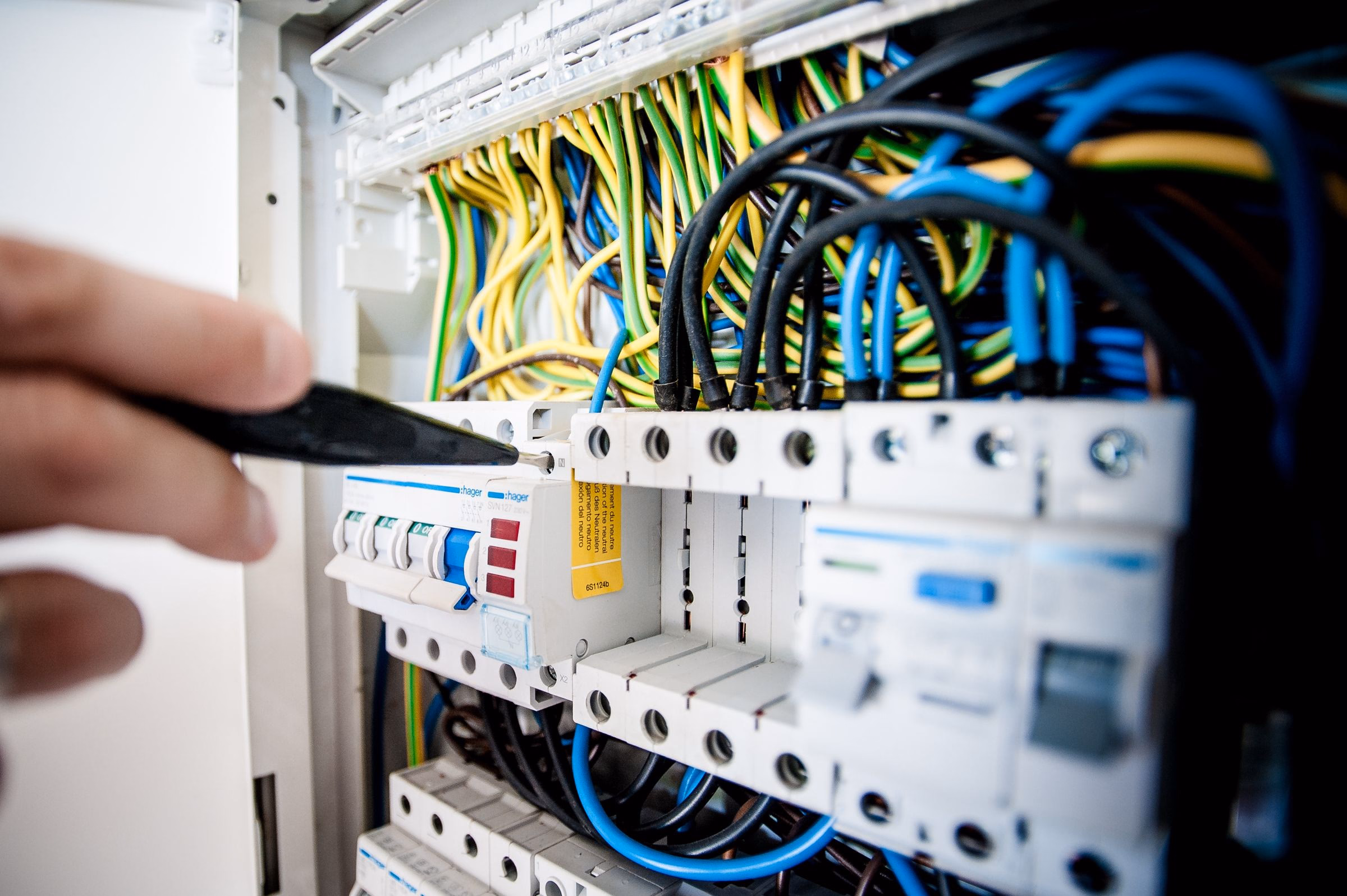 Electrician hands working on the inside of a circuit-breaker panel.