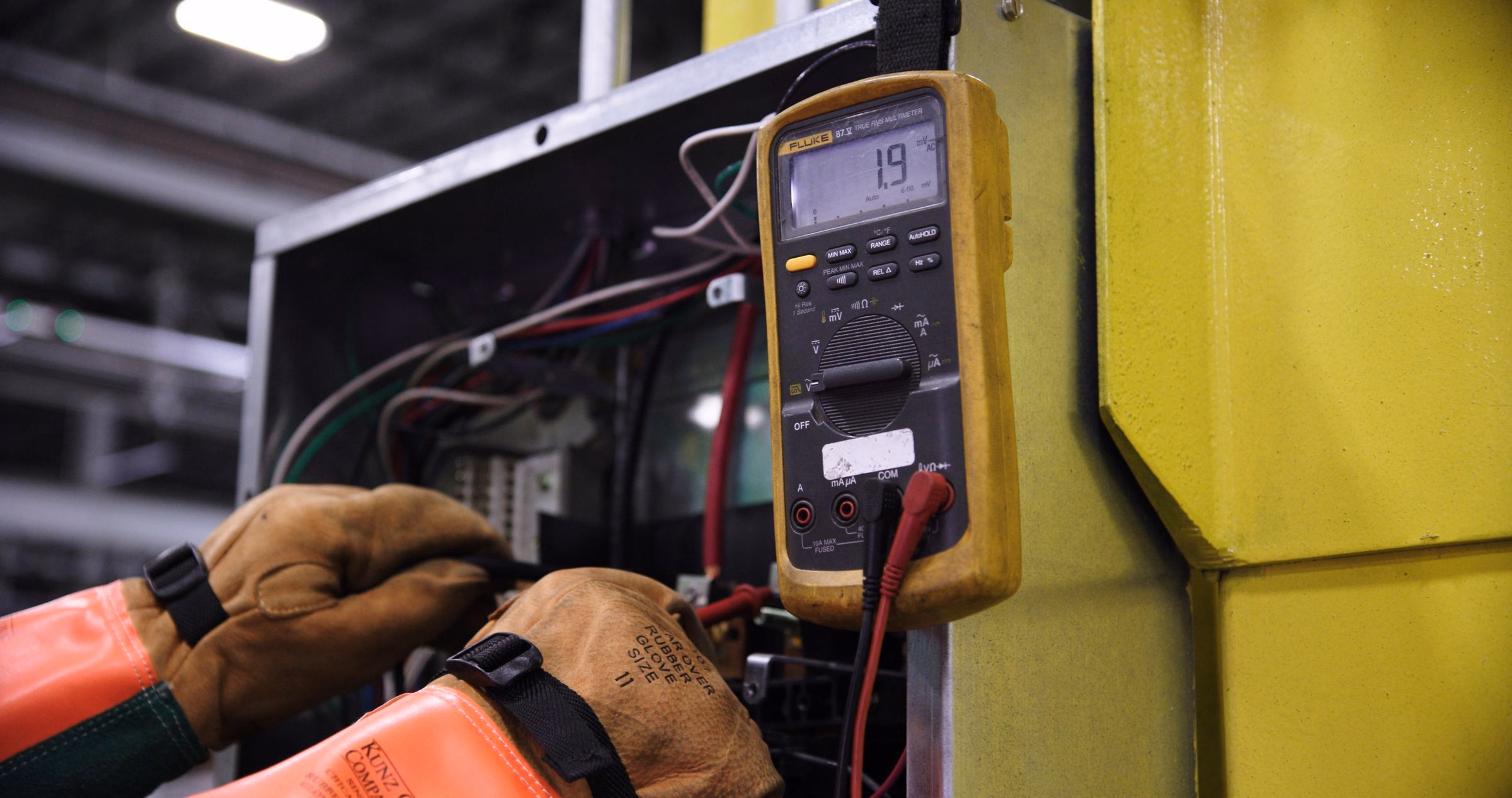 A multimeter probe taking a reading on a busbar.