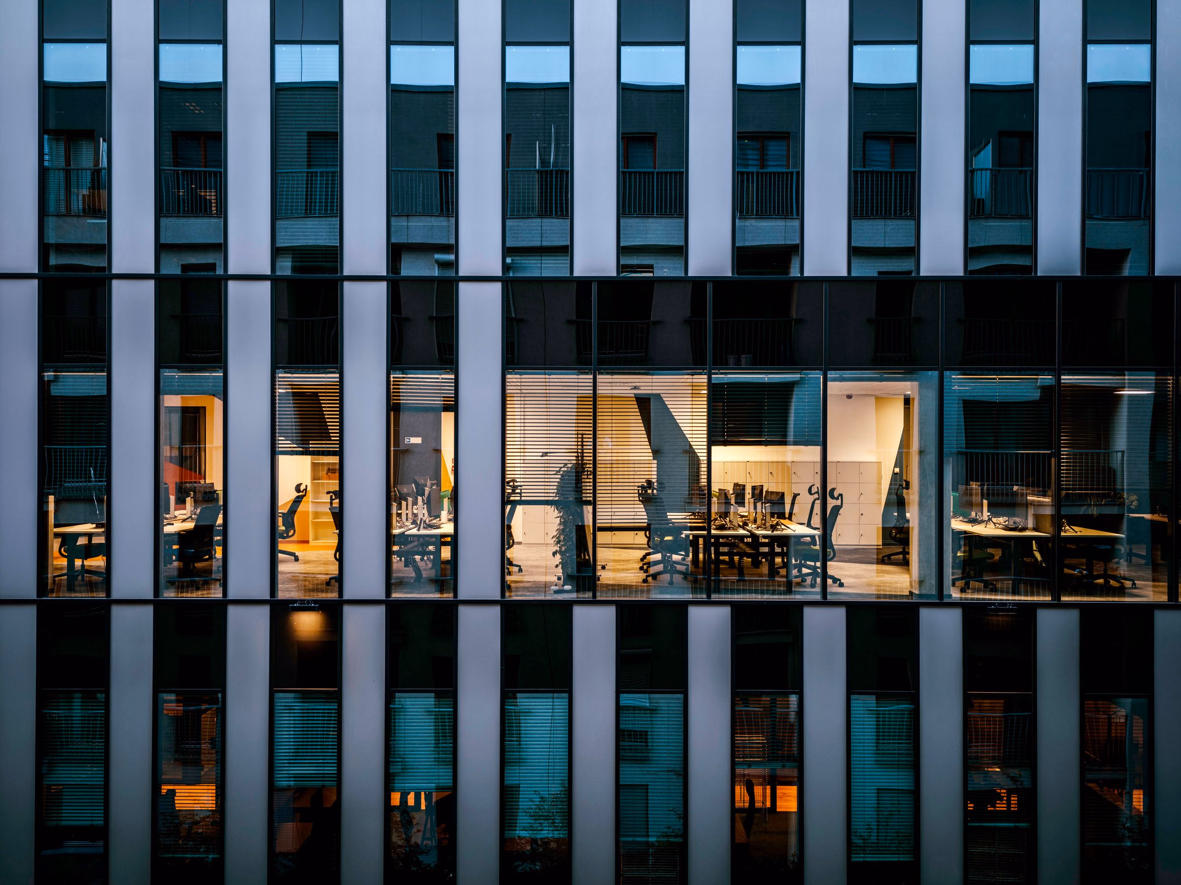 Modern glass office tower interior at night, looking through the curtain wall.