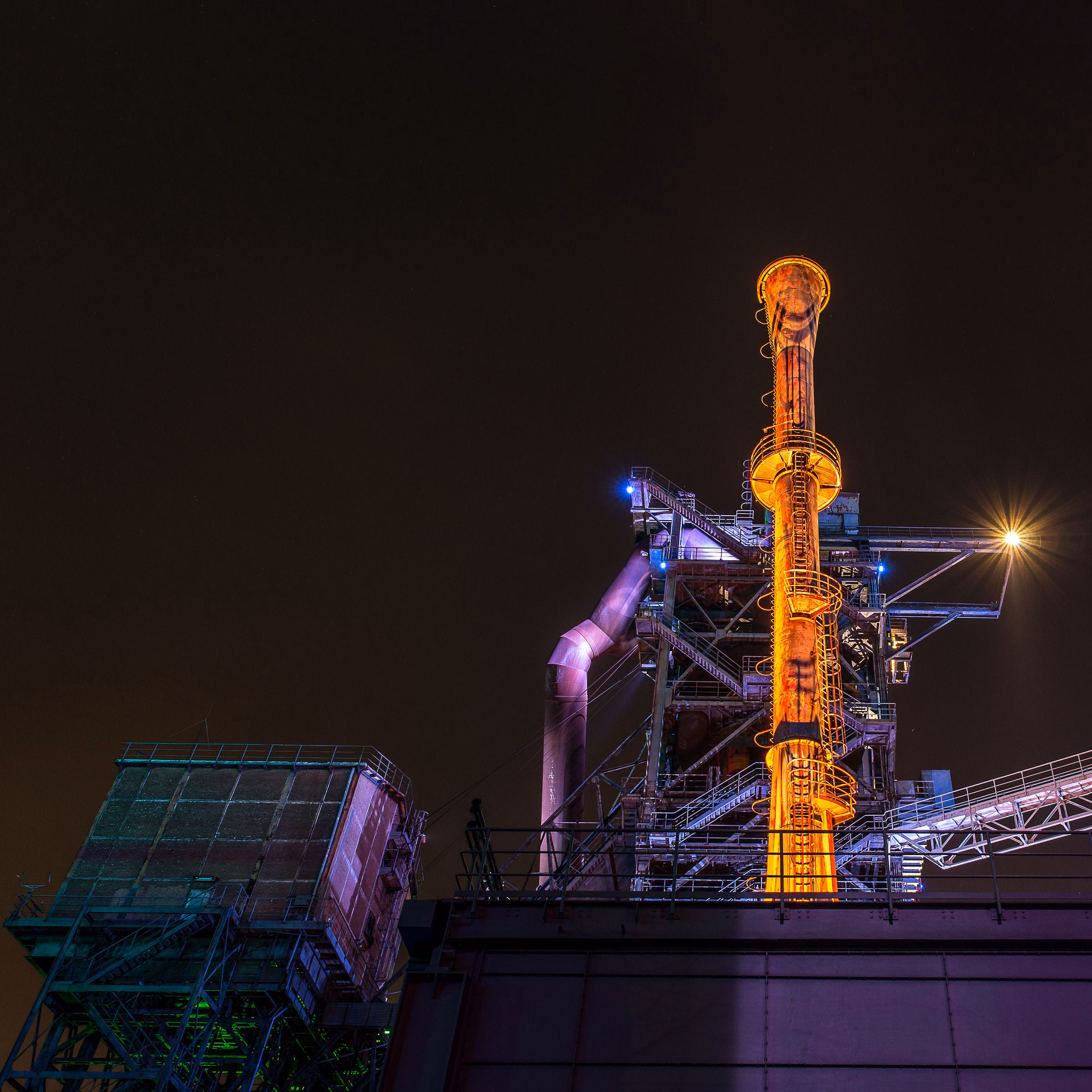 Industrial facility lit from within at night.